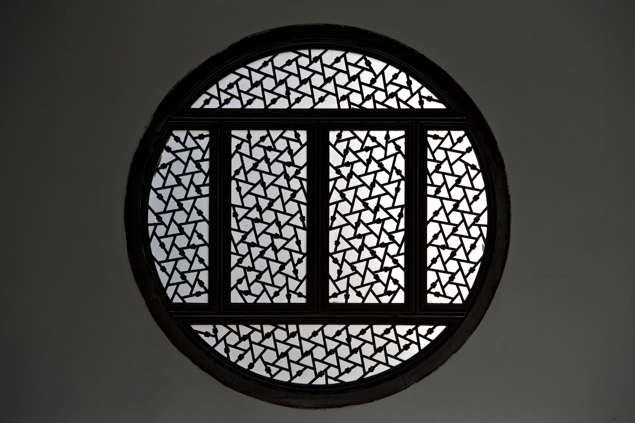 A round decorative window with intricate geometric latticework at the Humble Administrator’s Garden