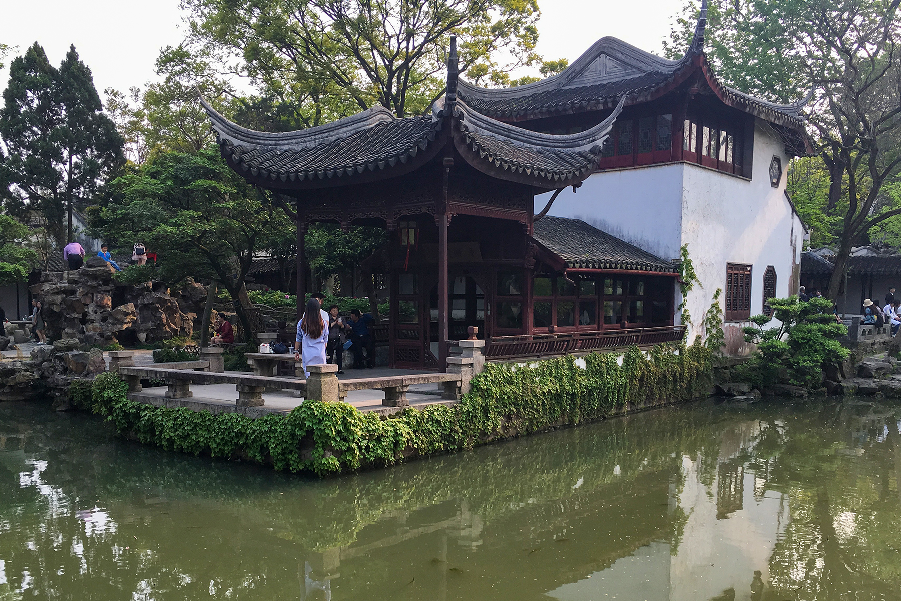 A waterside building at the Humble Administrator’s Garden, with curved tiled roofs, rocks and reflections in the pond
